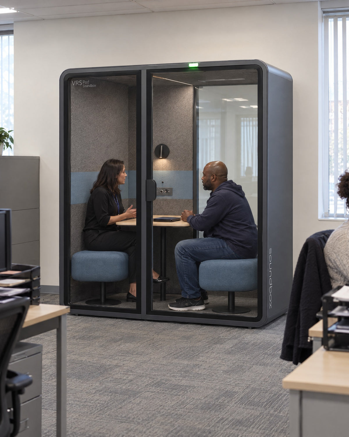 SoundBox VRS Comfort in a municipal social services office, a caseworker and a client talking privately inside. Illustration.