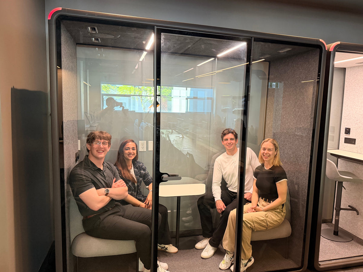 Four people sitting together inside a Quiet Cabins Collaborative room