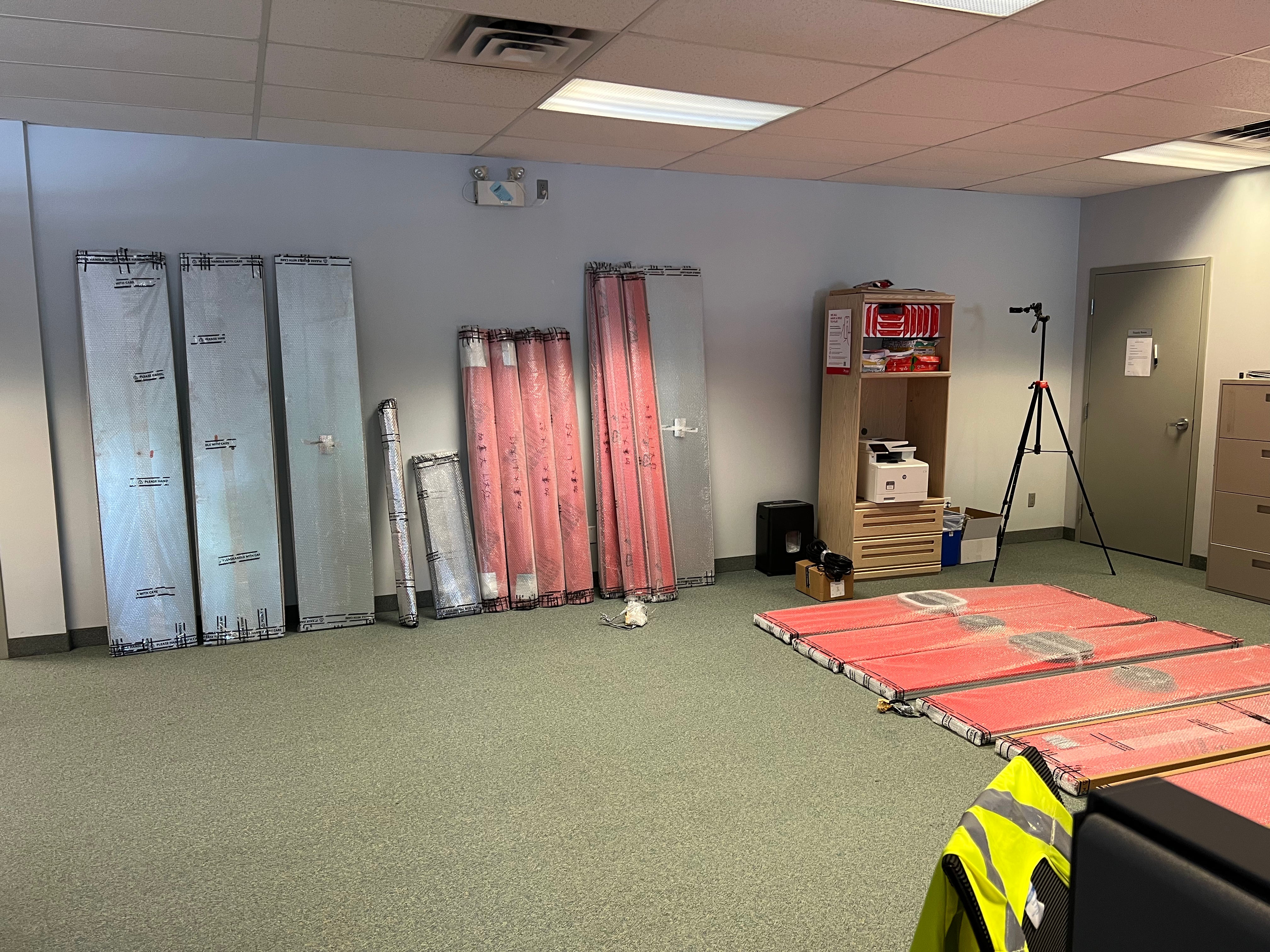 Panels arrive flat and go up in the passenger elevator. No crane, no loading dock required.