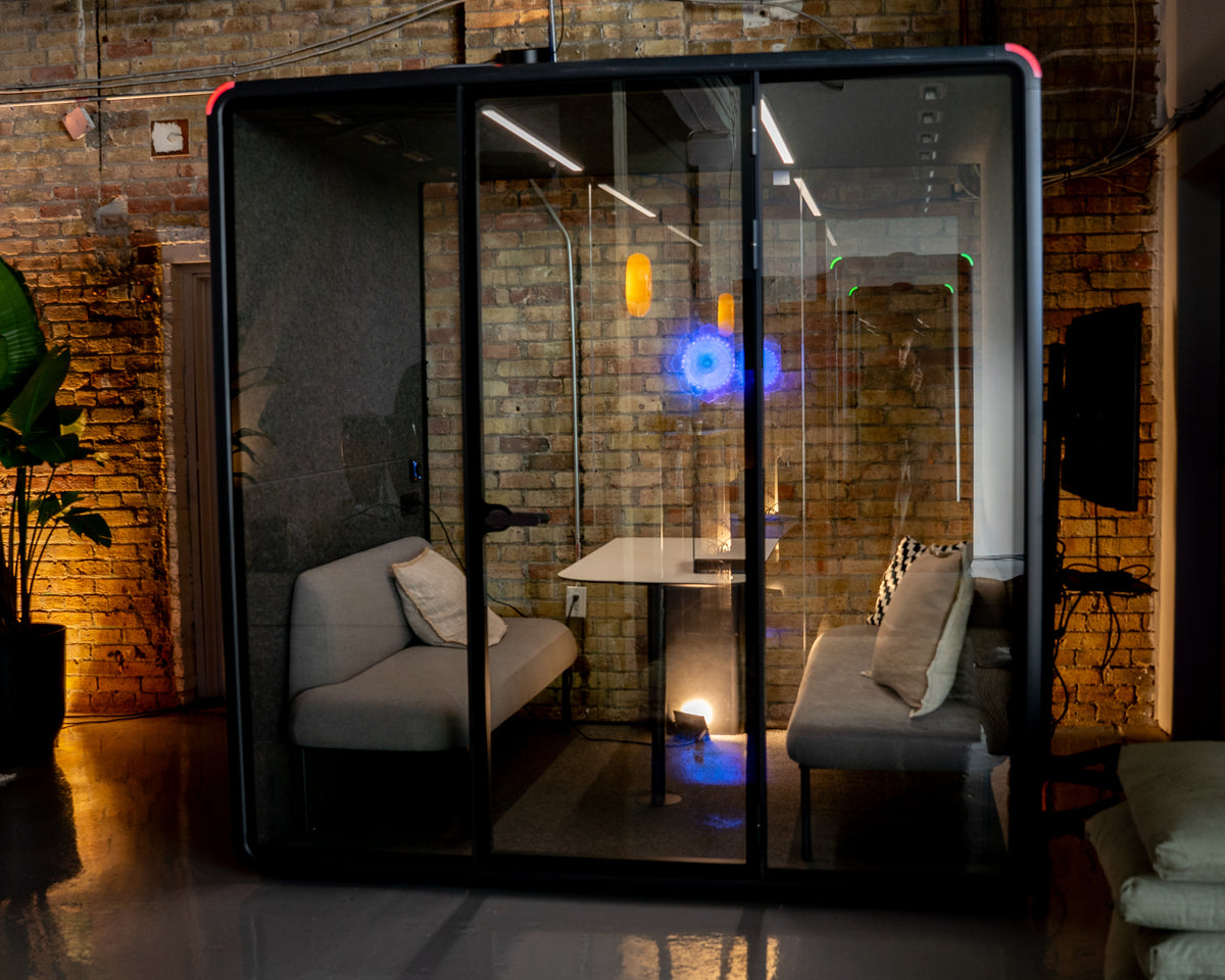 A Quiet Cabins Collaborative Booth with facing bench seating, installed against an exposed brick wall in a Canadian office