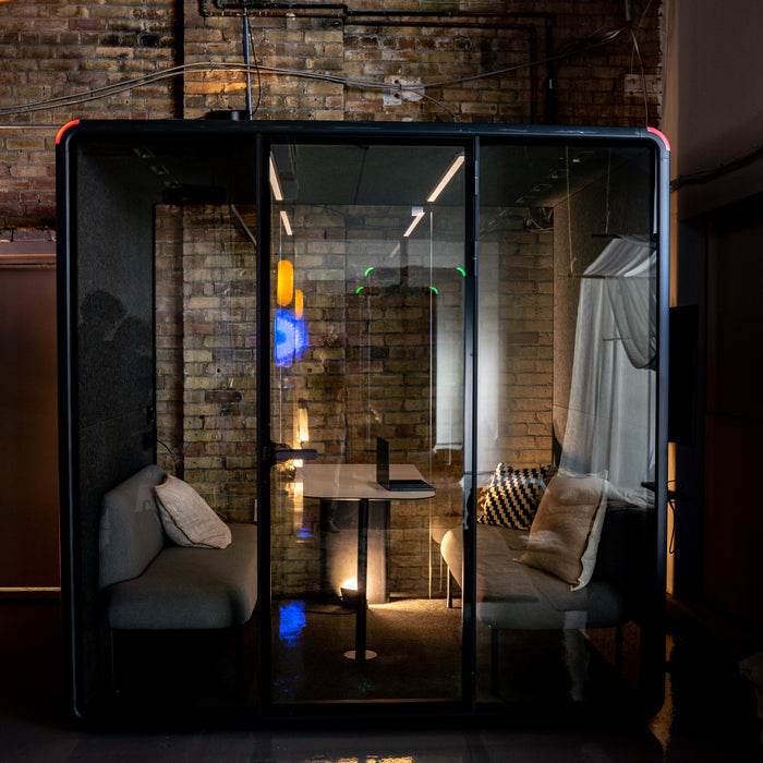 The lit interior of a Collaborative Booth with a laptop open on the table