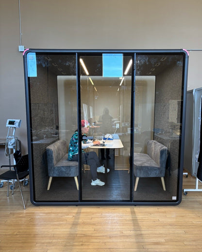 A CMHA staff member working inside a Quiet Cabins Collaborative booth in Oshawa