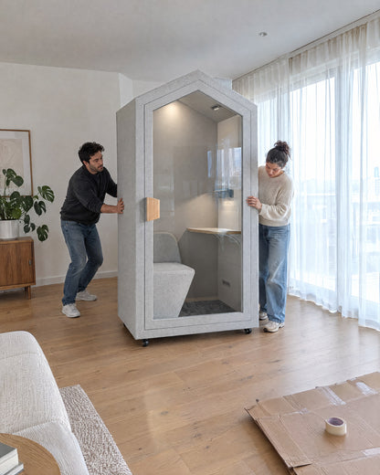 Two people rolling the Home Pod on its casters into place in a condo living room. Illustration.