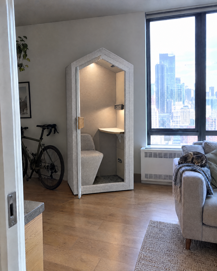 Home Pod against the wall next to the window of a small condo with a city view, door slightly open. Illustration.
