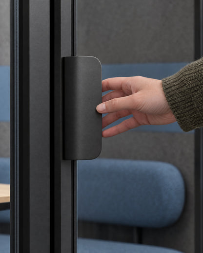 Hand reaching for the flat dark satin door pull of a SoundBox VRS Collaborative. Illustration.