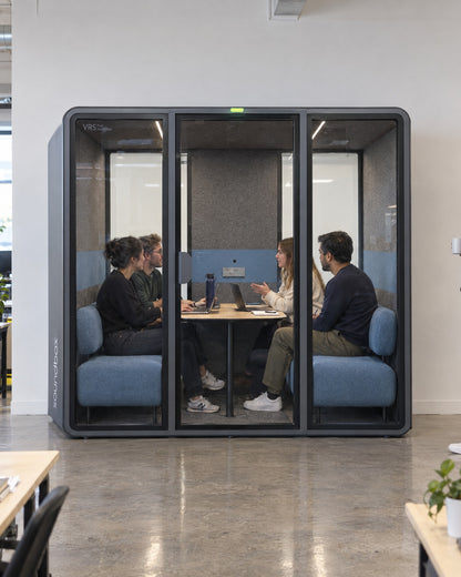 SoundBox VRS Collaborative in an open-plan office, four colleagues meeting inside on facing sofas, one colleague outside. Illustration.