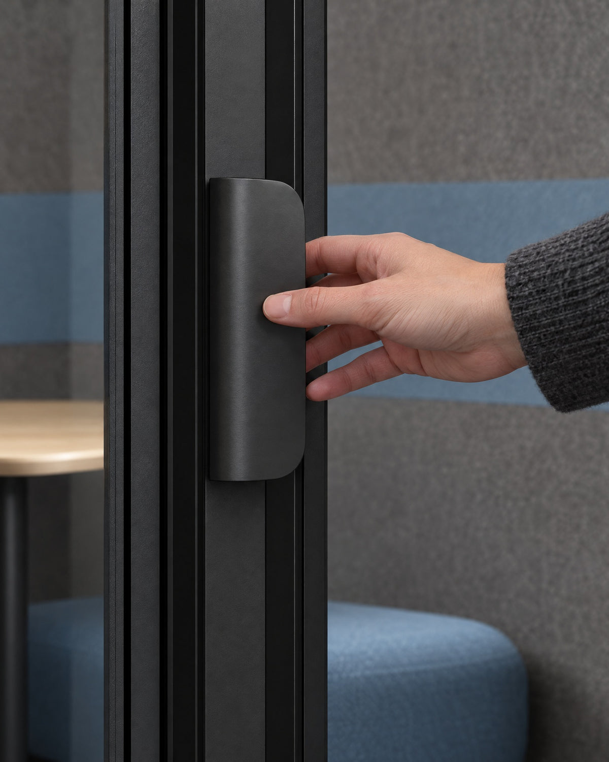 Hand reaching for the flat dark satin door pull at the centre mullion of a SoundBox VRS Comfort. Illustration.