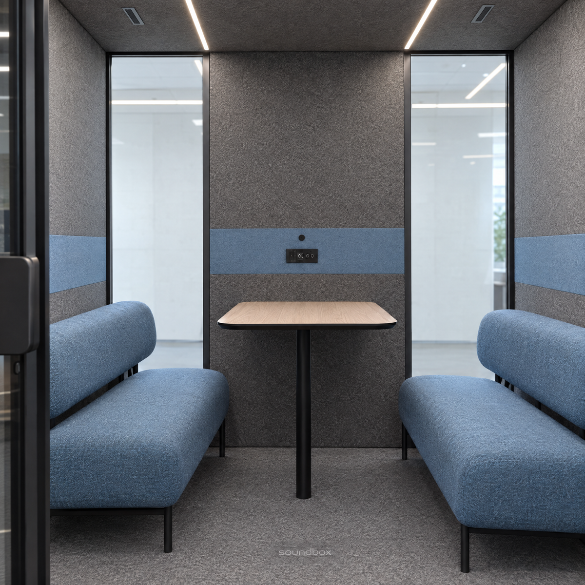 Inside the SoundBox VRS Double from the open door: a wide, shallow room with two dusty blue sofas facing each other, an oak table at the middle of the back wall, control panel on the felt, wide glass at both ends of the back wall. Illustration.
