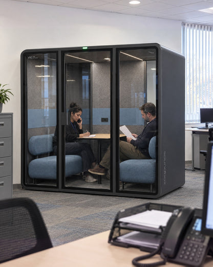 SoundBox VRS Double in a public service office seen from a nearby desk, one person inside on the phone and another reading a form. Illustration.