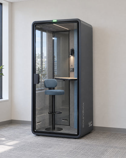 SoundBox VRS Single in a bright office corner by a window, door closed, green available light on. Illustration.