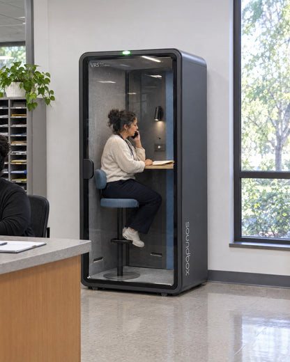SoundBox VRS Single in a school main office, a counsellor inside on a quiet phone call. Illustration.