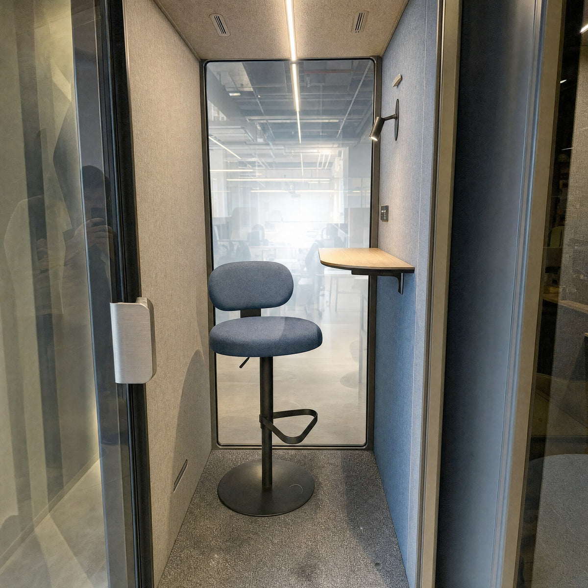 Inside the SoundBox VRS Single: glass back wall, greige felt, oak shelf, lamp and control panel at the far end of the right wall