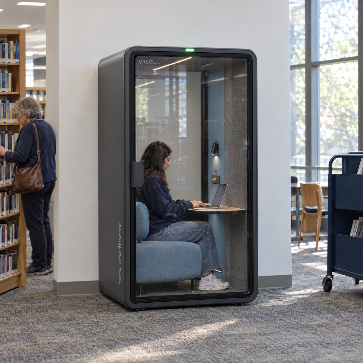 SoundBox VRS Single Comfort in a public library, a student inside working on a laptop. Illustration.